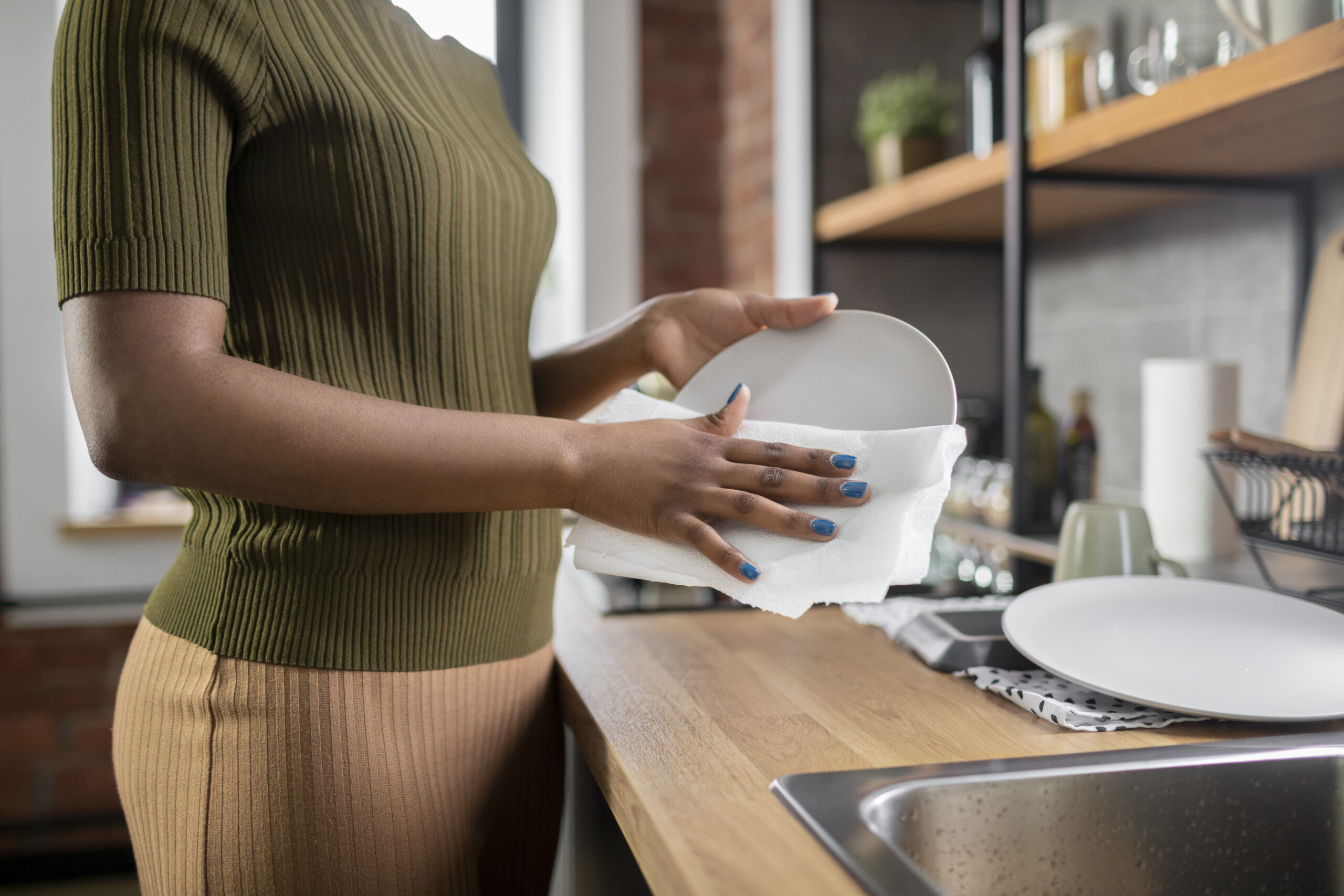 a woman cleaning plates near the kitchen sink